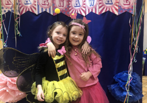 Dwie dziewczynki w strojy pszczółki i motylka pozują do zdjęcia.